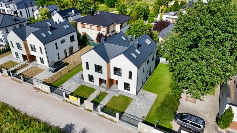 Bliźniak z lotu ptaka przy ulicy: dwa ogrody, kostka podjazdu, sąsiednie dachy i drzewa