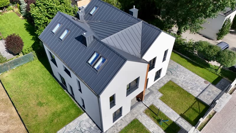 Bliźniak z góry: dwuspadowy dach z oknami połaciowymi, dwa ogrody i kostka podjazdu